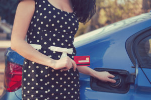 Closeup of a woman with credit card opening fuel tank of her new car