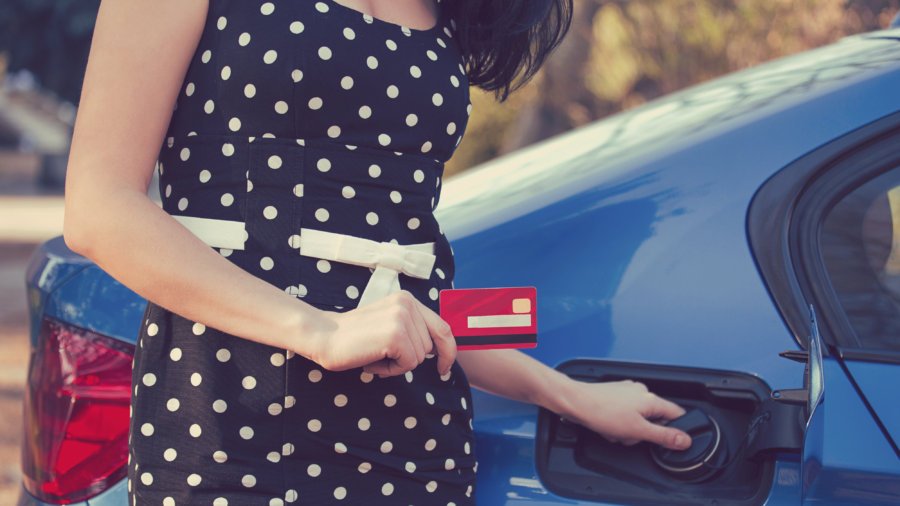 Closeup of a woman with credit card opening fuel tank of her new car