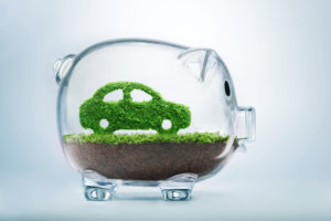 Green energy concept with grass growing in shape of car inside transparent piggy bank