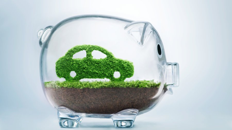 Green energy concept with grass growing in shape of car inside transparent piggy bank