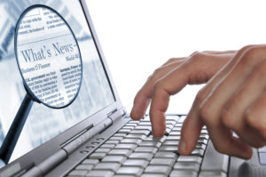 Man's hands are entering some words on the laptop keyboard for the Internet news. Both images you may buy separately here: laptop with hands and magnifying glass