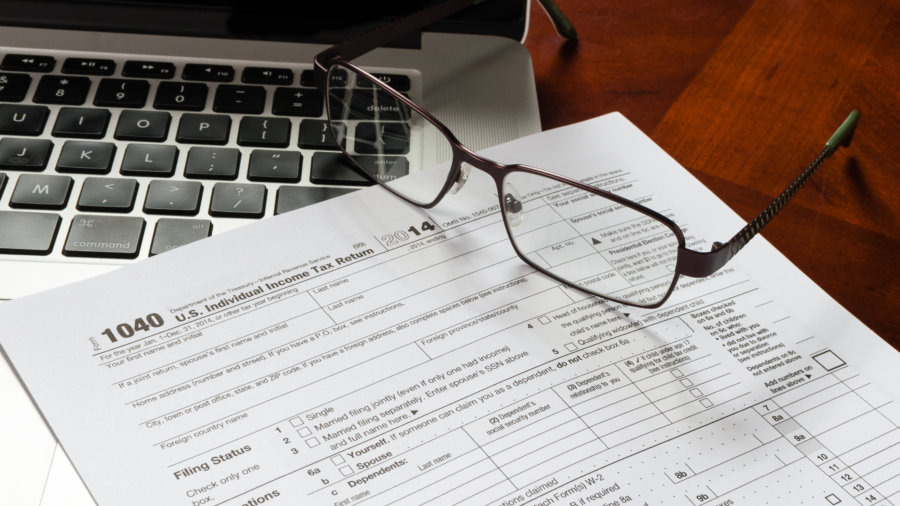 1040 income tax return form with MacBook and glasses